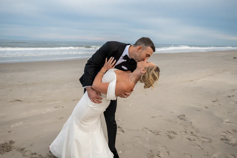 A couple sharing a joyful moment on the beach, photographed by Say I Do Studios